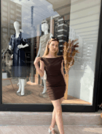 Bardot Yakalı Kahverengi Mini Elbise giyen sarı saçlı kadın.