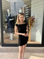 Siyah Geniş Yakalı Mini elbise giyen, sarı saçlı kadın.