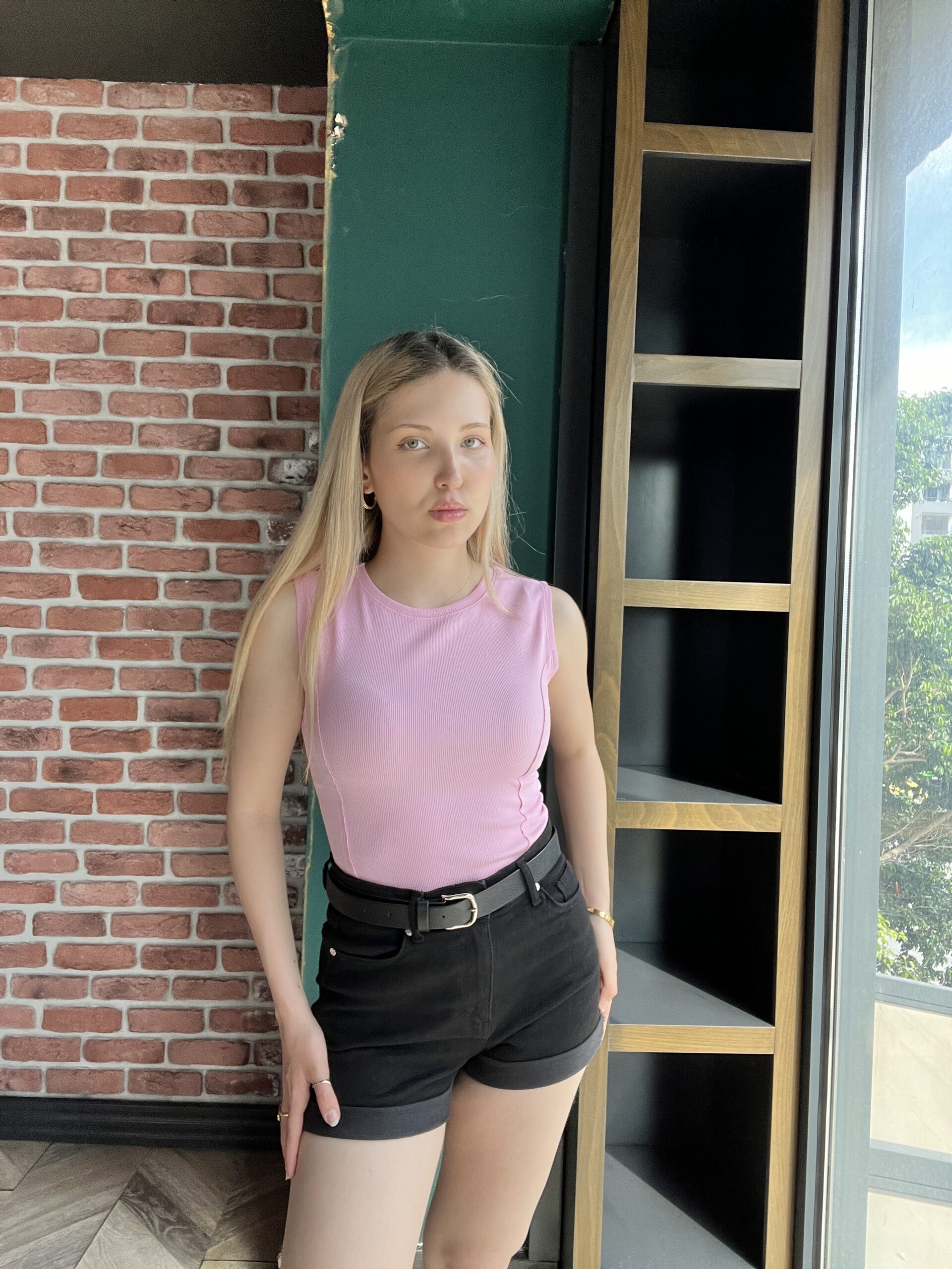 Pembe Fitilli Bluz ve siyah şort giyen sarı saçlı kadın.